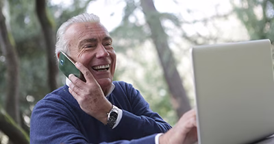Retraité au téléphone devant un ordinateur